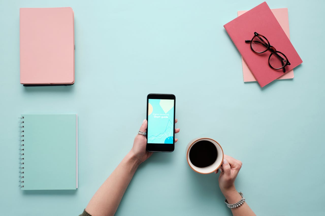 Person Holding a Smartphone and a Cup of Coffee